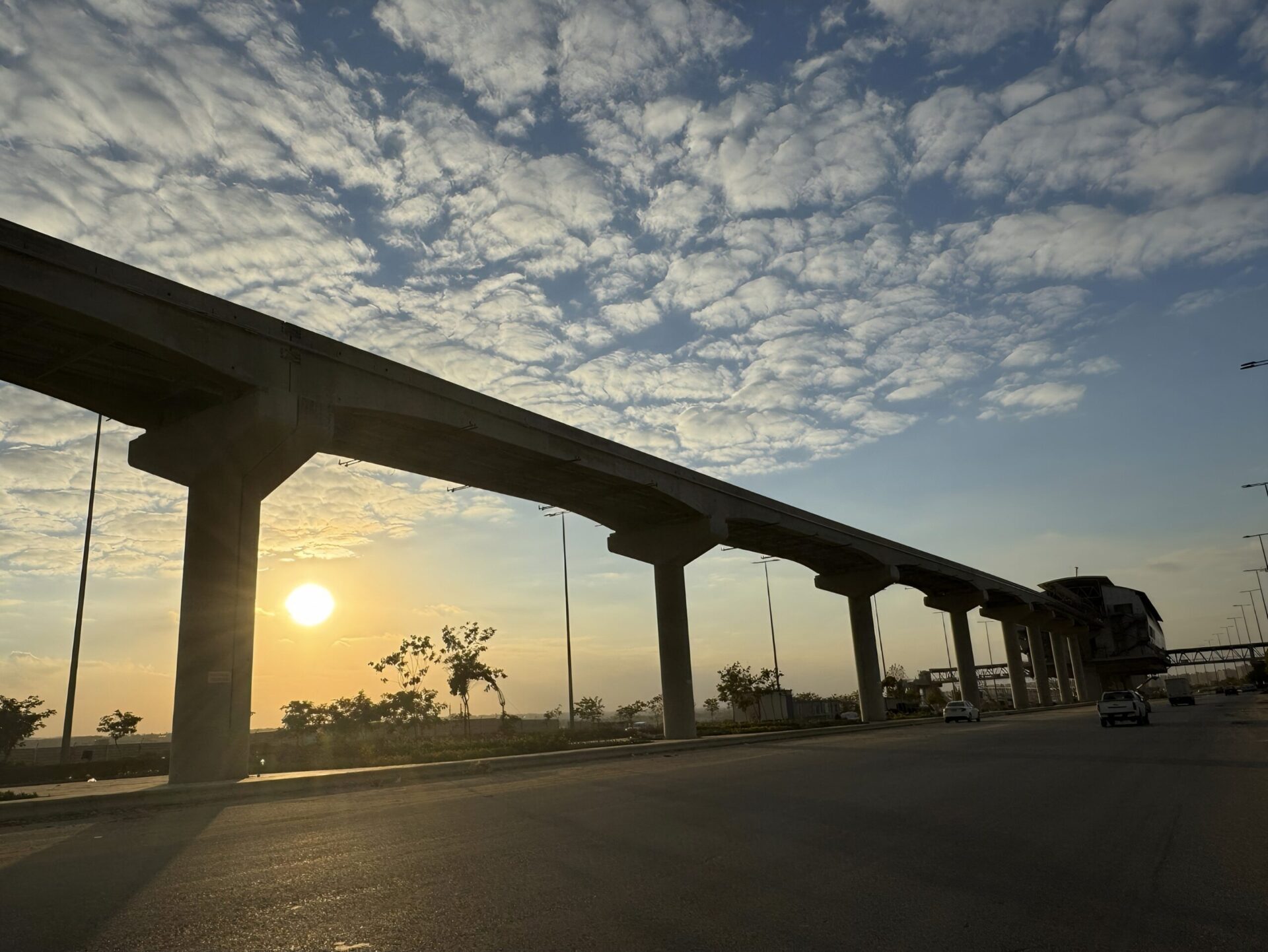 An elevated monorail running parallel to a road.