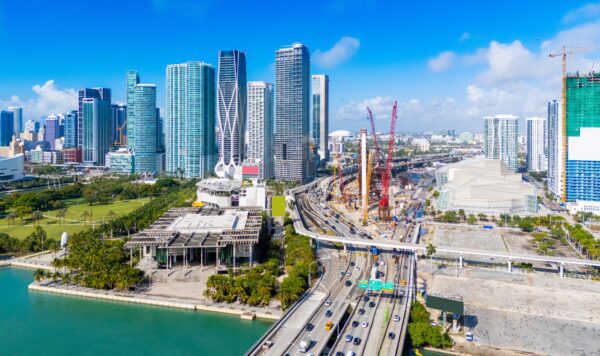drone footage of downtown miami on a sunny day with cars, roads, and buildings 