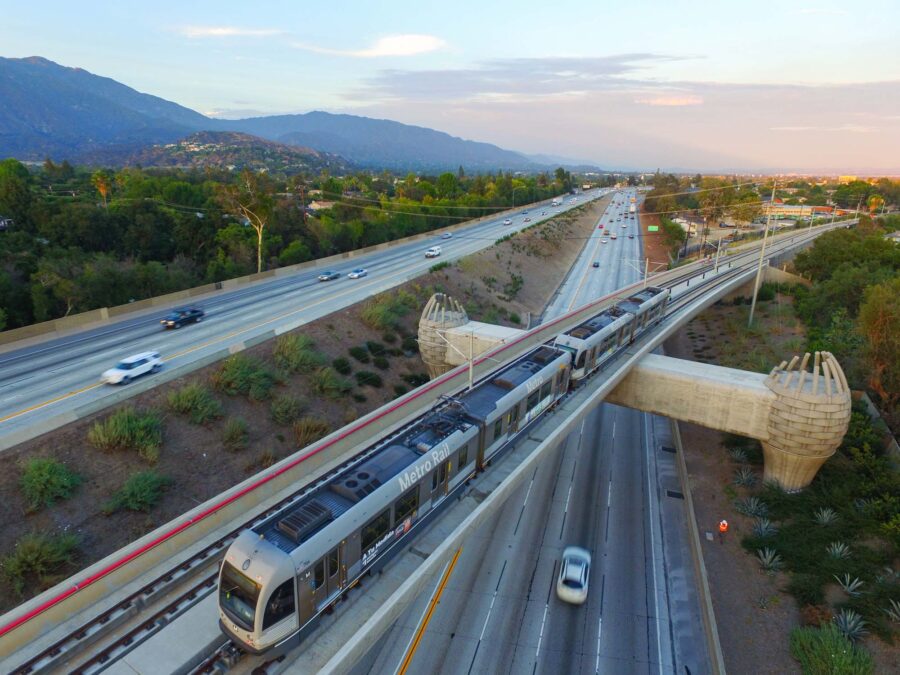 A metro train traversing across a bridge that spans over an interstate road.