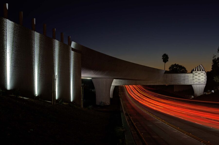 A metro bridge spanning over an interstate road at night.