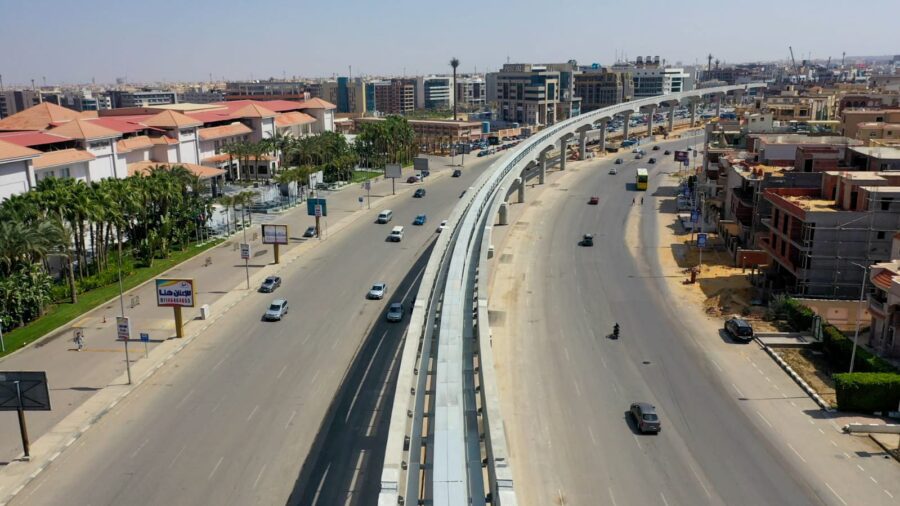 An elevated and curved monorail that runs in-between two roads that mirror the same curved path.