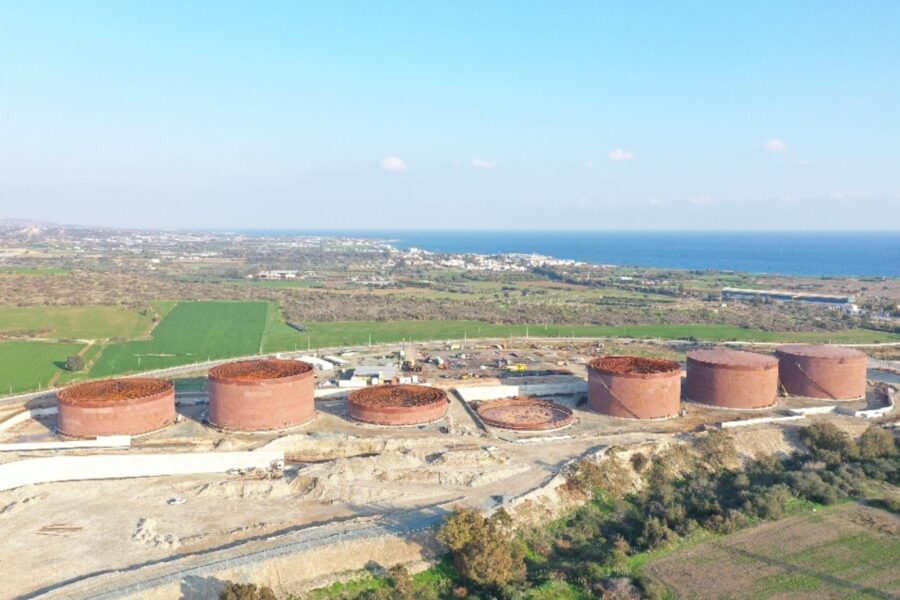 An aerial shot of seven large metal silos, five of which are in different stages of construction