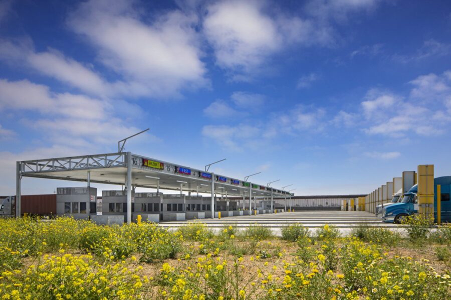A US/Mexico Border check point during the day with Semi trucks approaching.