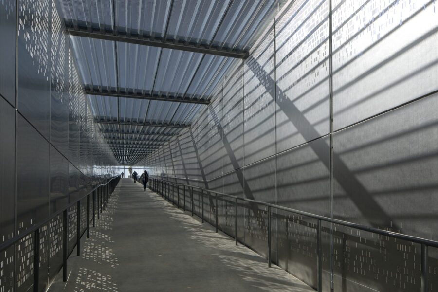 The interior of a covered pedestrian ramp with a fine metal mesh roof