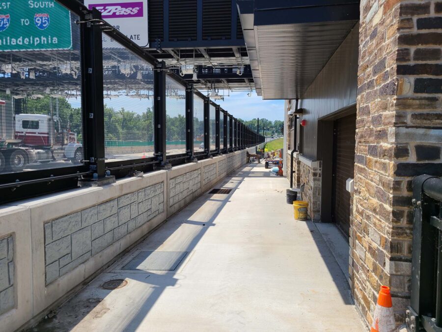 A sidewalk superheated from a busy highway but a brick and glass wall.