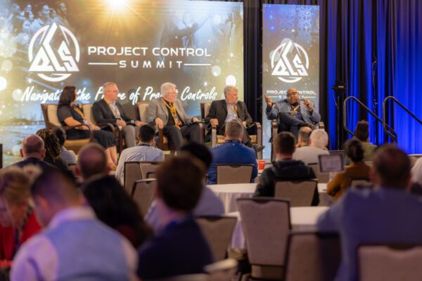 Crowd of people watch a panel of individuals speaking on a stage