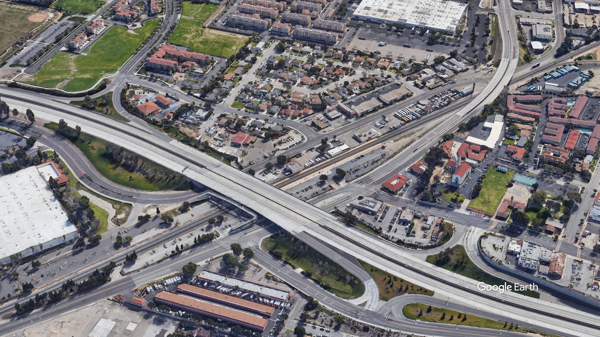 A satellite view of a highway stretching over a metro underpass station in the middle of a city.