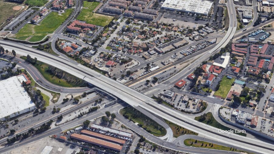 A satellite view of a highway stretching over a metro underpass station in the middle of a city.