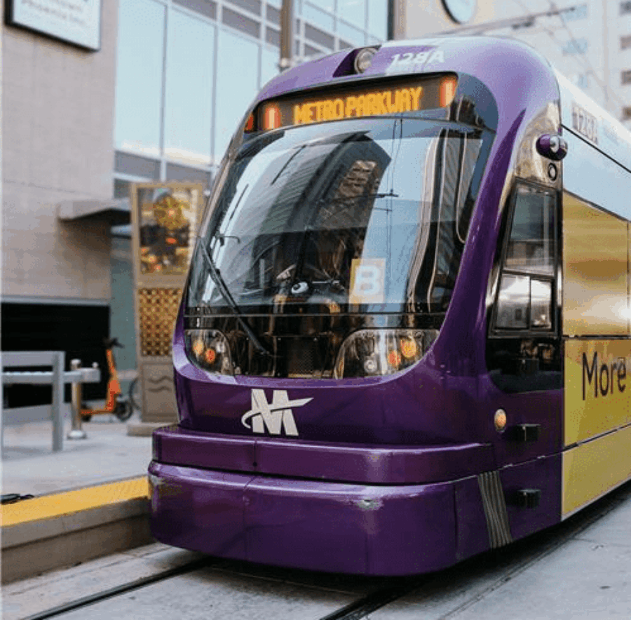 A light rail train stopped at a station in the middle of a city